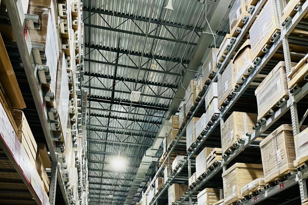 Hohe Regale mit Kartons in einem Lager als Beispiel für eine Unternehmenskooperation in der Logistik