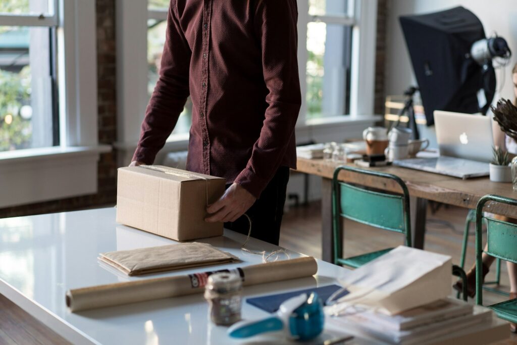 Bootstrapping im Versandhandel: Hände halten ein gepacktes Paket auf einem Tisch