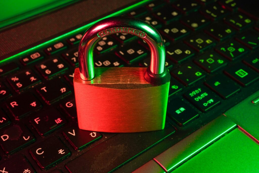 Rotes Vorhängeschloss auf einer schwarzen Computertastatur als Symbol für Cybersicherheit