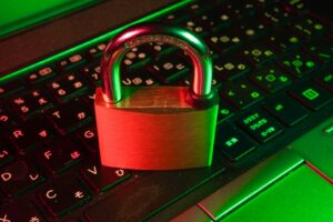 Rotes Vorhängeschloss auf einer schwarzen Computertastatur als Symbol für Cybersicherheit