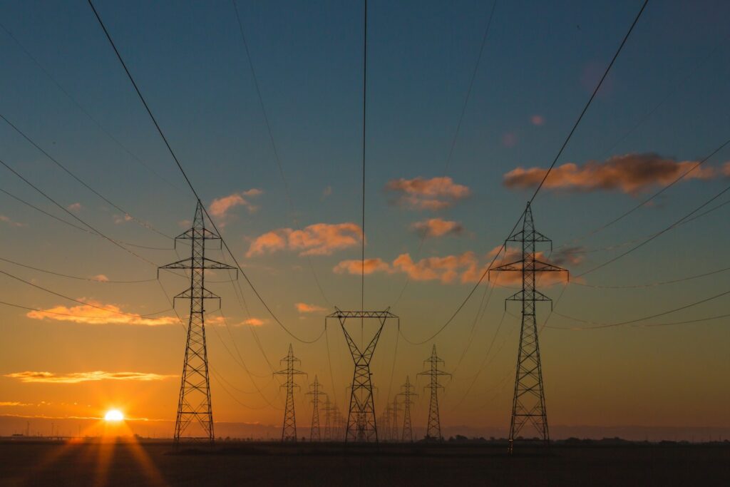 Hochspannungsmasten mit Stromleitungen vor dem Himmel als Symbol für Energiekosten Industrie