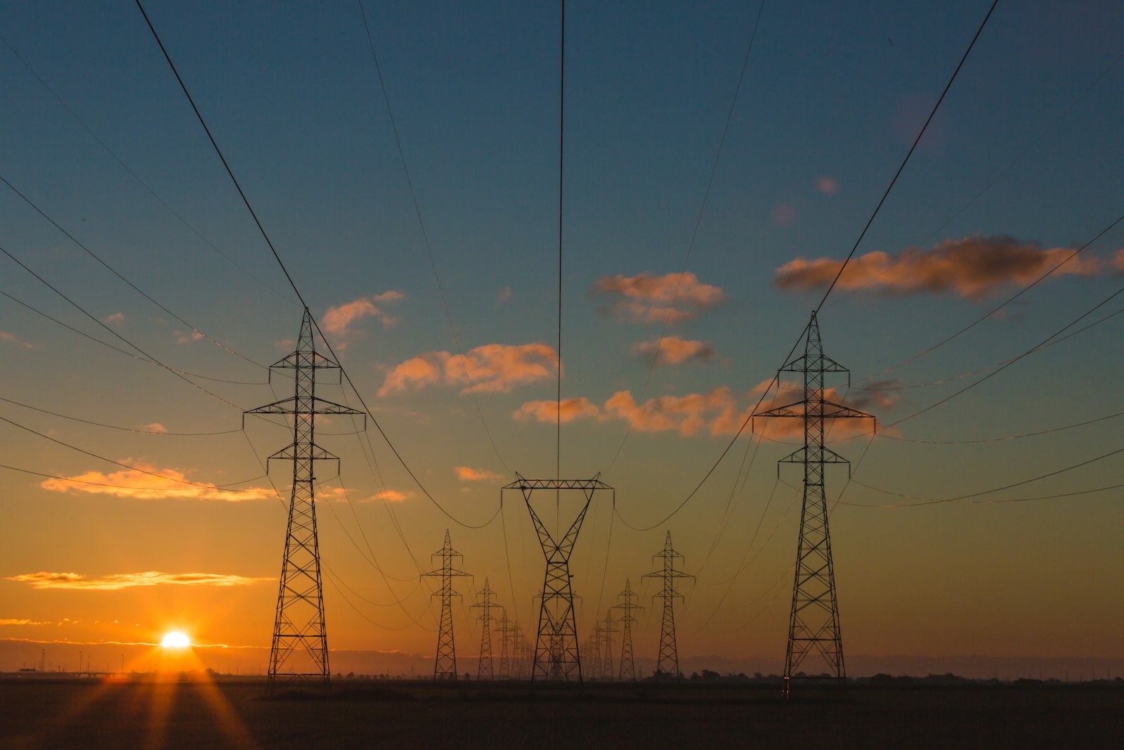 Hochspannungsmasten mit Stromleitungen vor dem Himmel als Symbol für Energiekosten Industrie