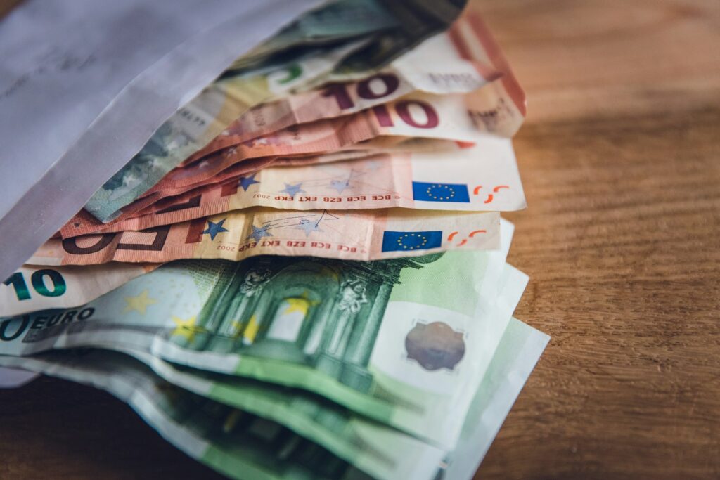 Euro-Banknoten auf einem Holztisch – der Leitzins bestimmt, was Geld für Unternehmen kostet