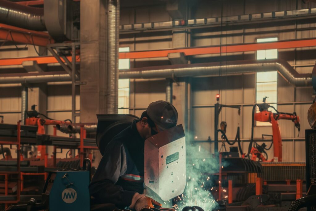 Fachkräftemangel in der Produktion: Schweißer arbeiten in einer Fabrikhalle an einer Maschine