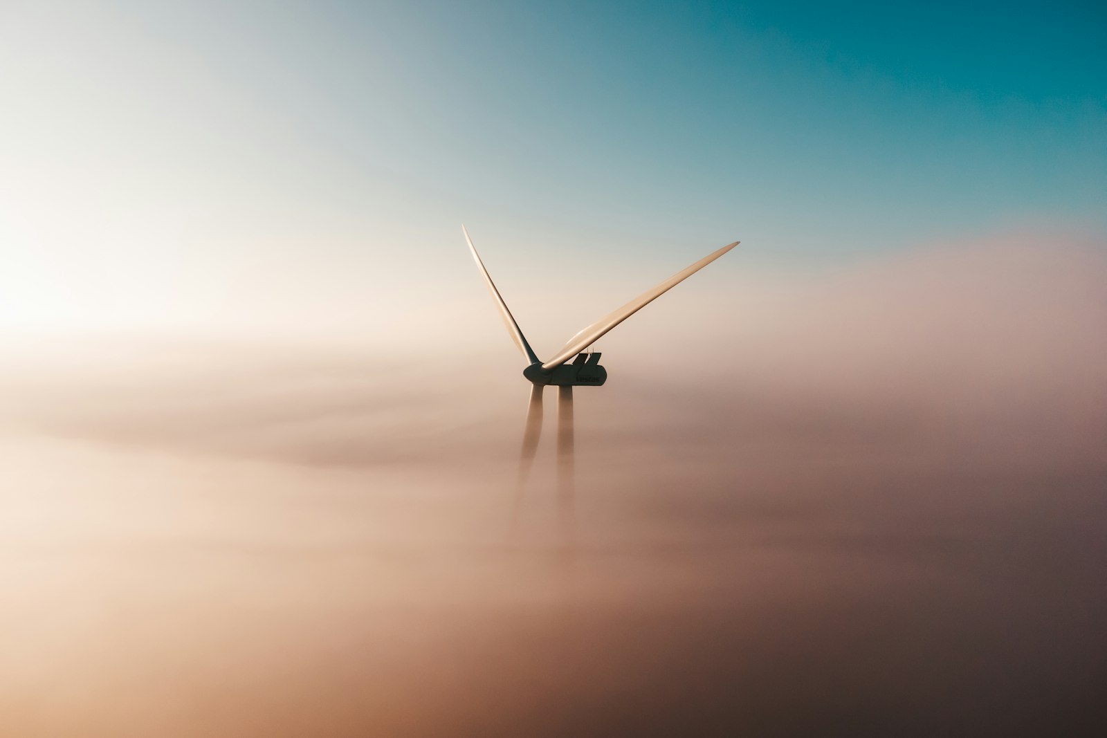 Windrad ragt bei Sonnenaufgang aus dem Nebel – Sinnbild für Projekte, die Green Bonds finanzieren