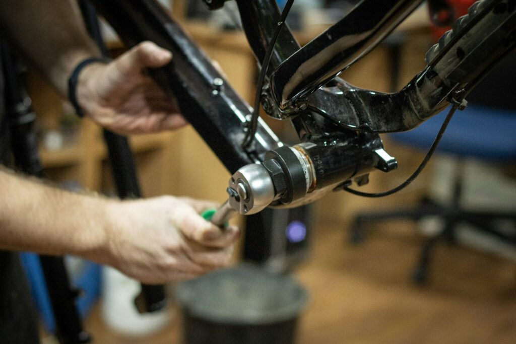 Hände reparieren ein Fahrrad in einer Werkstatt – Reparatur als Baustein der Kreislaufwirtschaft