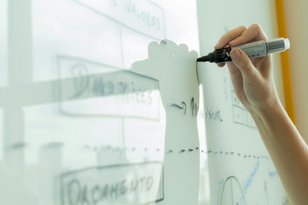 Hand zeichnet ein Ablaufdiagramm auf ein Whiteboard als Vorarbeit für eine Low-Code-Anwendung