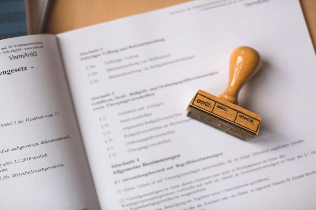 Holzstempel auf einem geöffneten deutschen Rechtsdokument als Sinnbild für Prüfung und Zustimmung