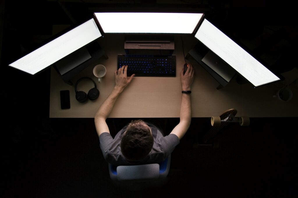 Entwickler arbeitet an einem Arbeitsplatz mit drei Monitoren an einer Anwendung auf Basis von Low-Code