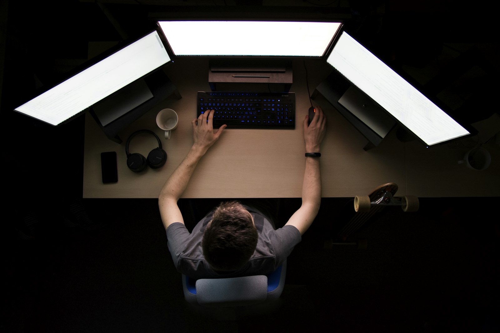 Entwickler arbeitet an einem Arbeitsplatz mit drei Monitoren an einer Anwendung auf Basis von Low-Code