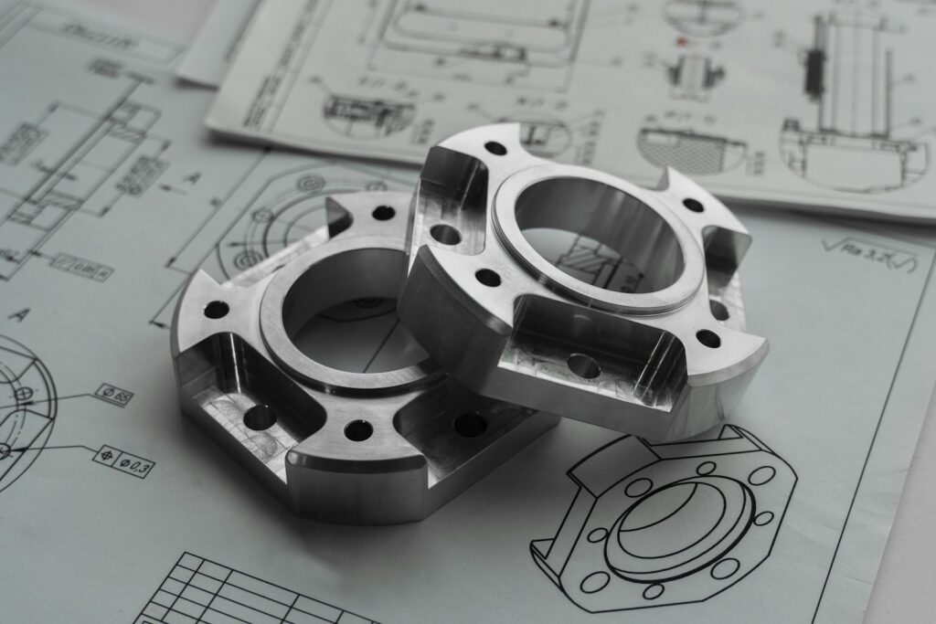 Metallbauteile auf technischen Zeichnungen als Symbol für Wissenssicherung in der Produktion
