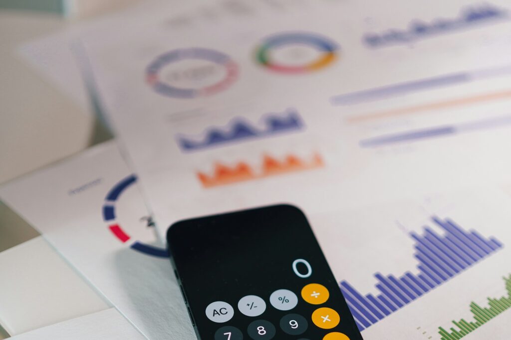 Taschenrechner-App auf einem Smartphone über ausgedruckten Finanzberichten – Routinearbeit, die KI im Controlling übernimmt