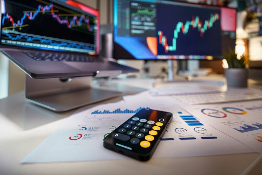 Taschenrechner auf dem Schreibtisch vor Finanzcharts bei der Planung einer Investitionsfinanzierung