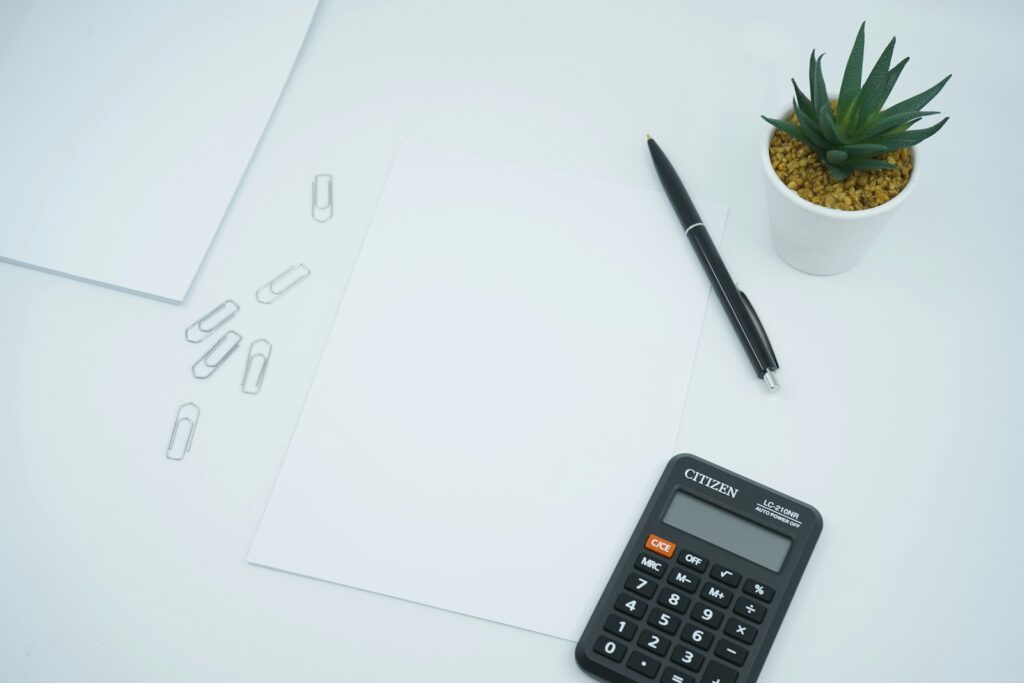 Taschenrechner und Stift auf Papier zur Vorbereitung auf Preisverhandlungen