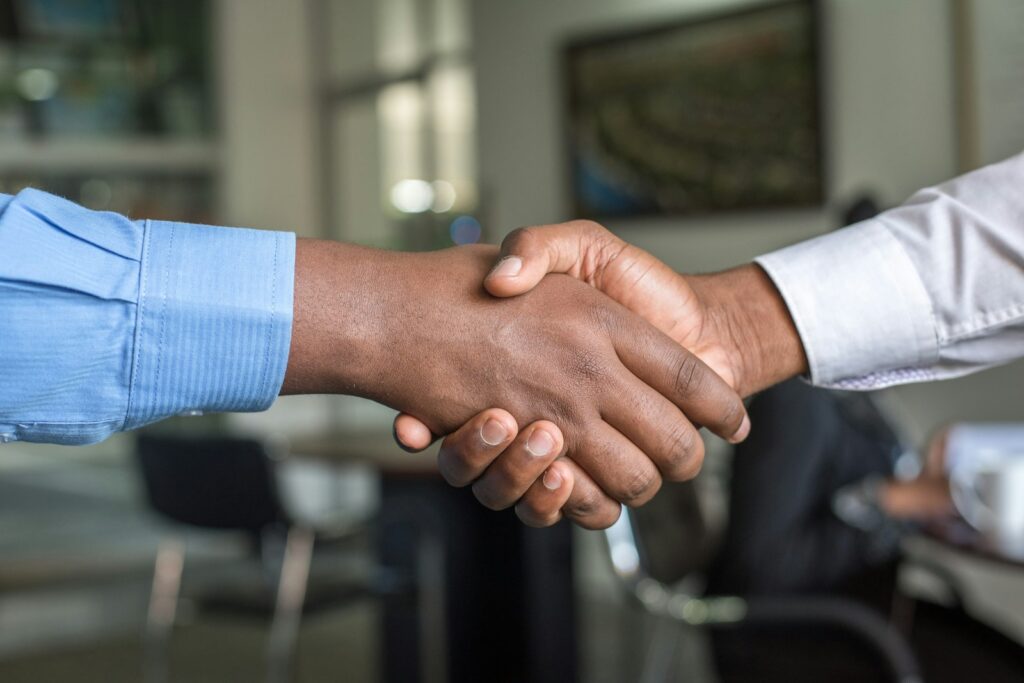Unternehmenskauf besiegelt: Zwei Personen geben sich im Büro zum Abschluss der Vereinbarung die Hand