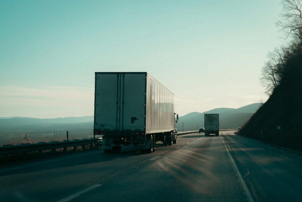 Zwei Sattelzüge auf einer Landstraße mit Bergblick – der CO2-Preis verteuert Diesel im Güterverkehr